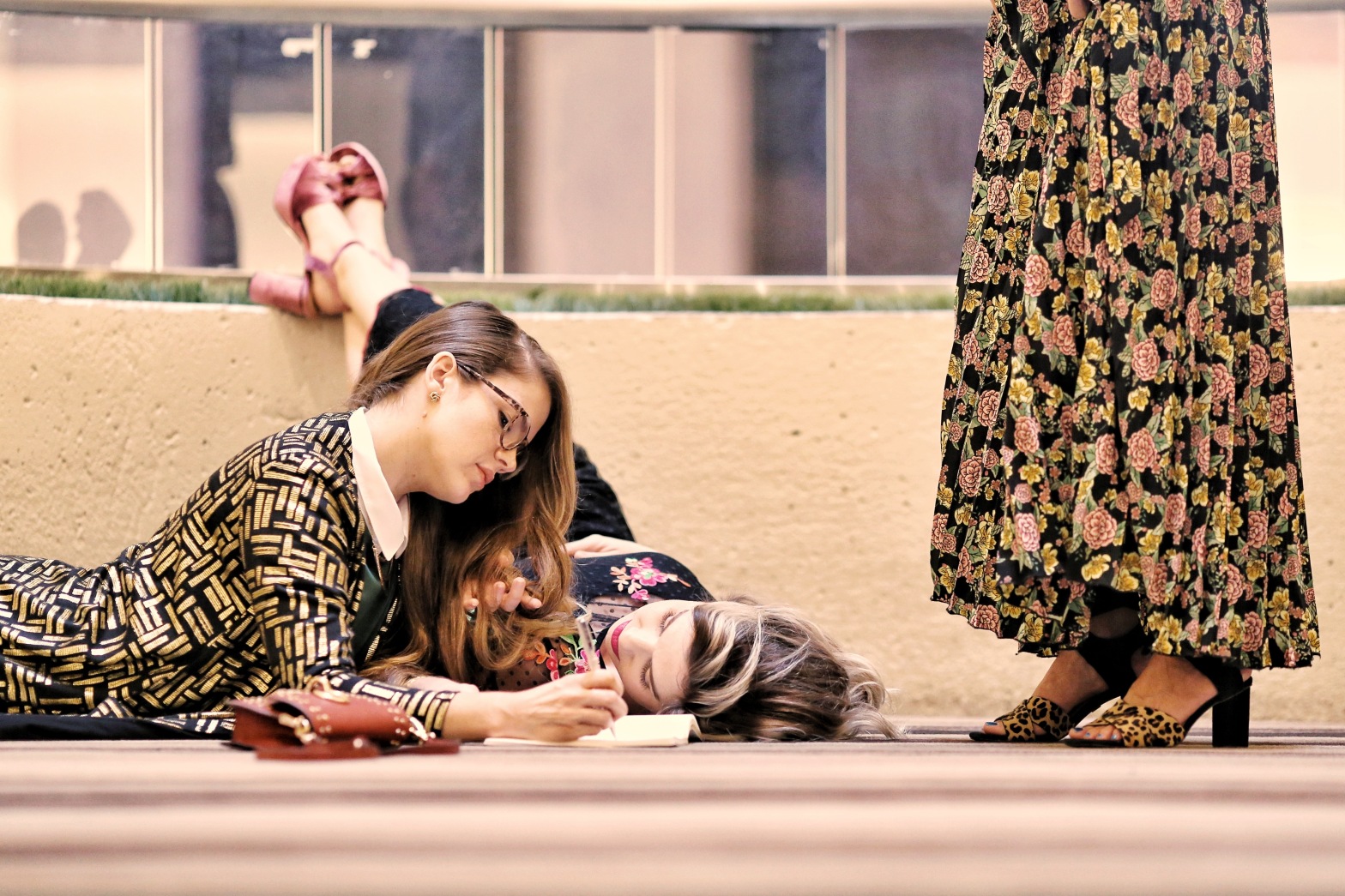 Katie Dunlavy, Lularoe boutique owner, of The Pearl Pages in a patterned dress lying on the ground next to her daughter and writing in a notebook.