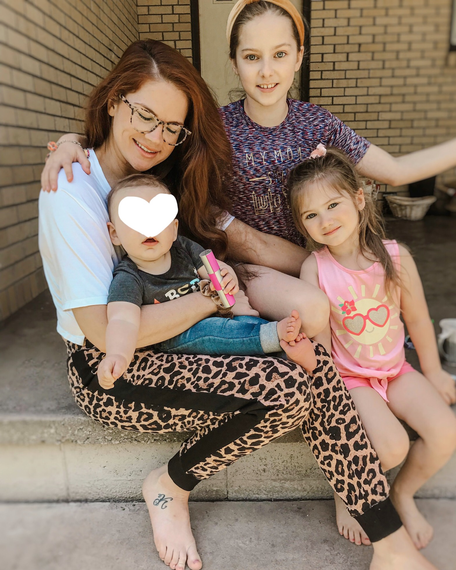 Katie Dunlavy of The Pearl Pages sitting n concrete steps with her children and foster son, wearing leopard print Lularoe Jax joggers.